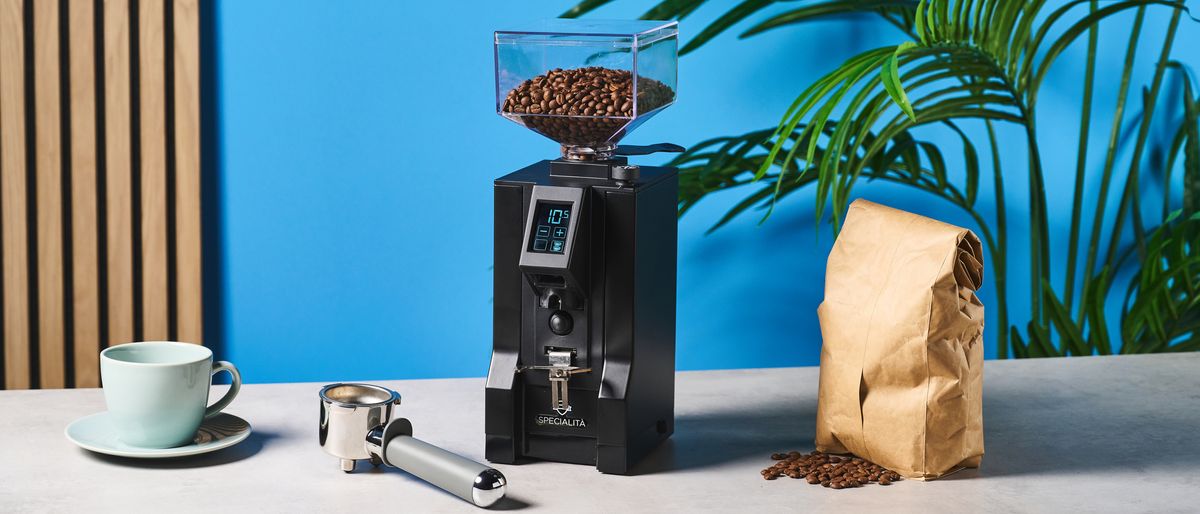 The Eureka Mignon Specialita coffee grinder on a kitchen counter against a blue wall