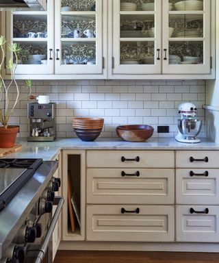 A white kitchen with glass fronted cabinets and iron vintage kitchen hardware