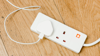 charger plugged into a dual extension lead on a wooden surface