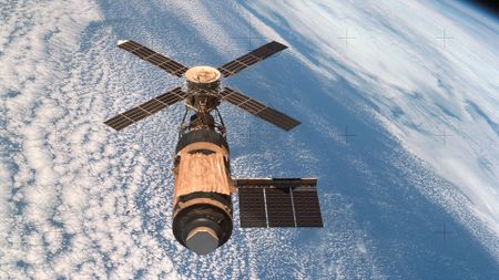 a one-module space station with extended solar arrays is seen in orbit above Earth