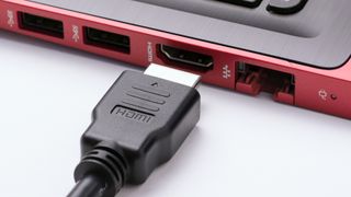 An HDMI 2.1 cable being put into the side of a laptop