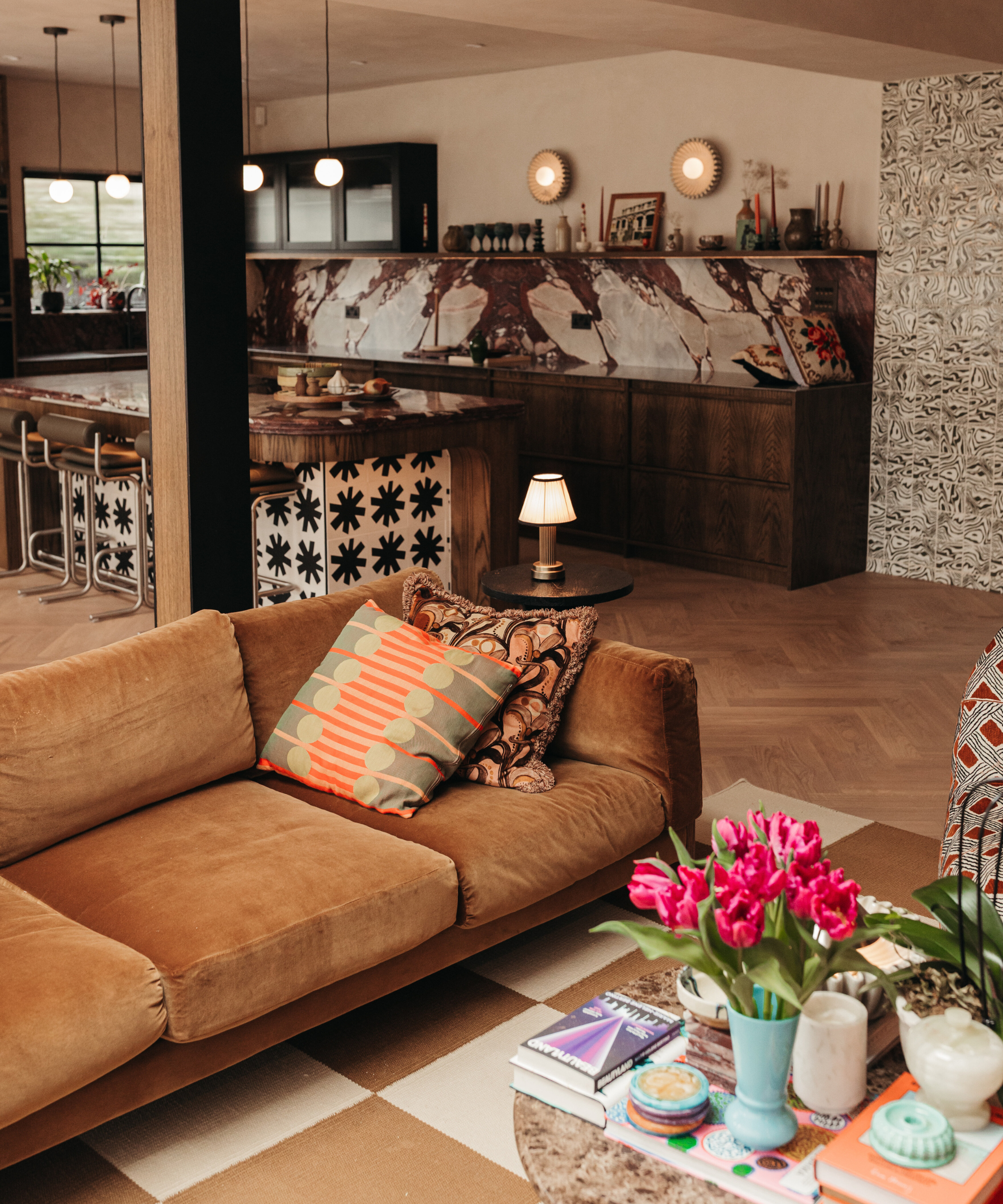 Kitchen with living area and orange sofa and bold patterned marble and tiled cabinetry