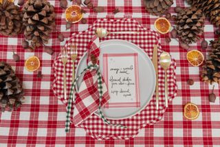 A Christmas table setting with red gingham tablecloths and contrasting gingham ribbons