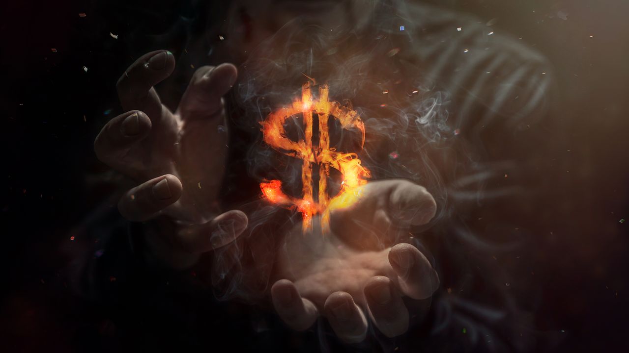 man with hands cupping dollar bill sign that&amp;#039;s on fire