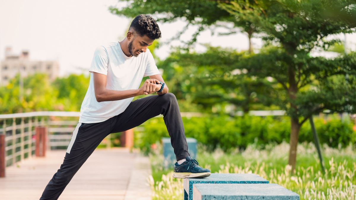 Man stretching and checking GPS watch before run