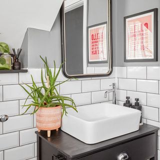 Basin on wooden stand in bathroom, surrounded by white metro tiles