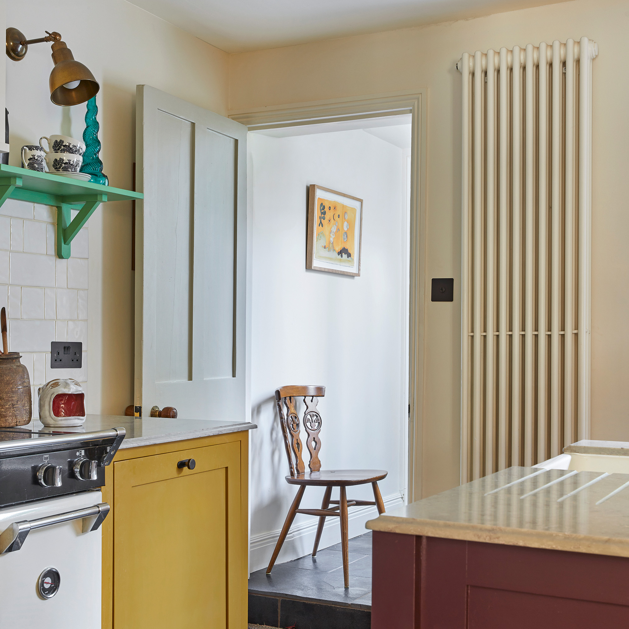 kitchen with yellow cabinet, green open shelf and plum island viewed towards an open door with a radiator to the right