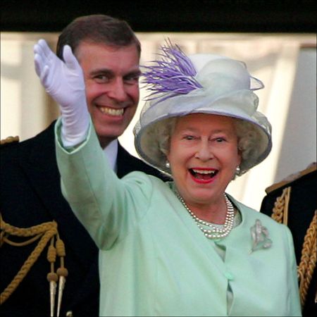 Queen Elizabeth II wears a mint green coat dress and matching hat with pearls and waves from the Buckingham Palace balcony while son ex-Prince Andrew laughs behind her