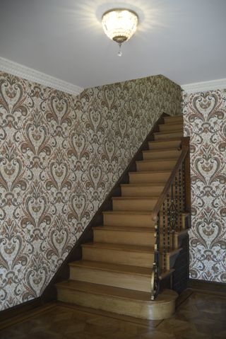 Wooden stairs with dated patterned wallpaper