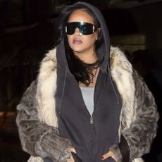 Rihanna layered an oversize hoodie underneath a Saint Laurent fur coat with flared jeans