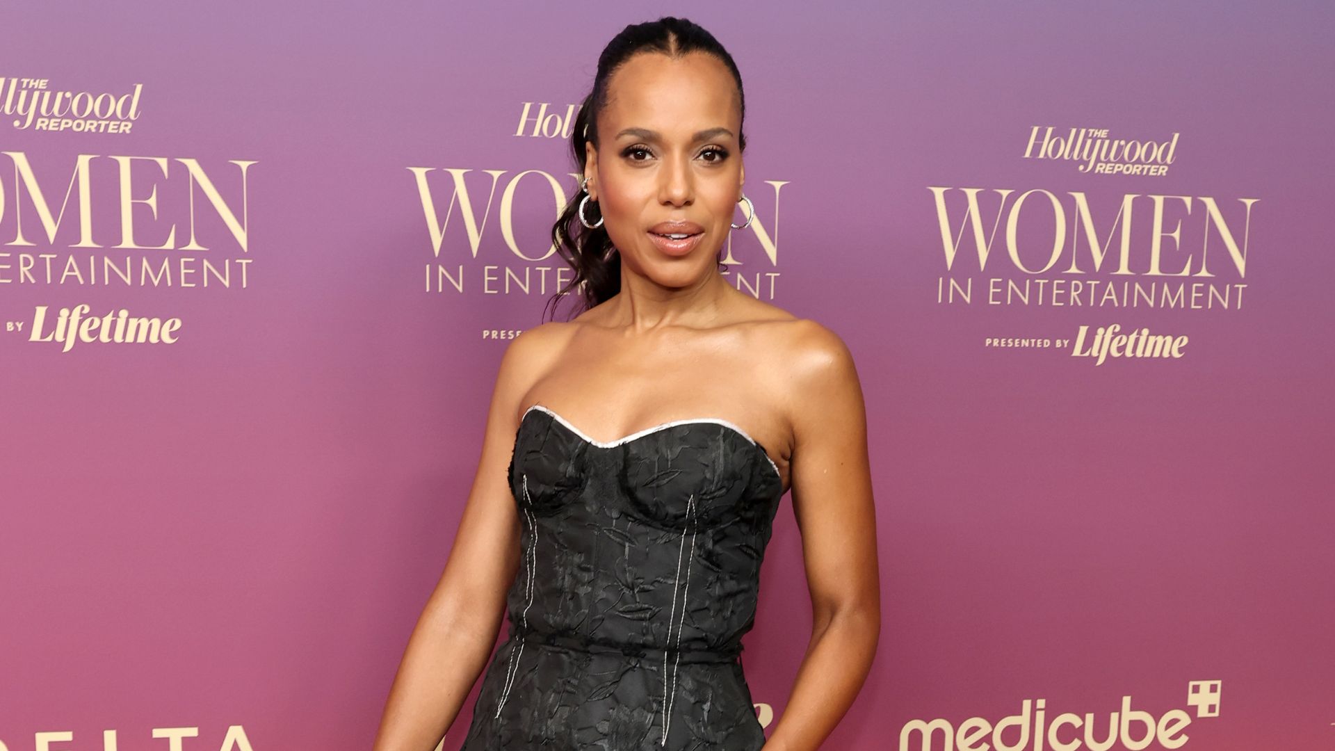 Kerry Washington poses on the red carper wearing a black two-piece skirt set with silver high heels.