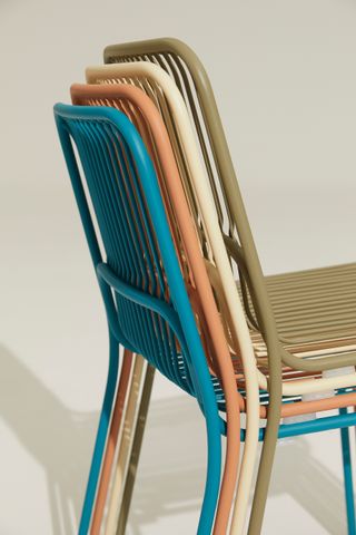 Stack of metal garden chairs in green, white pink and blue