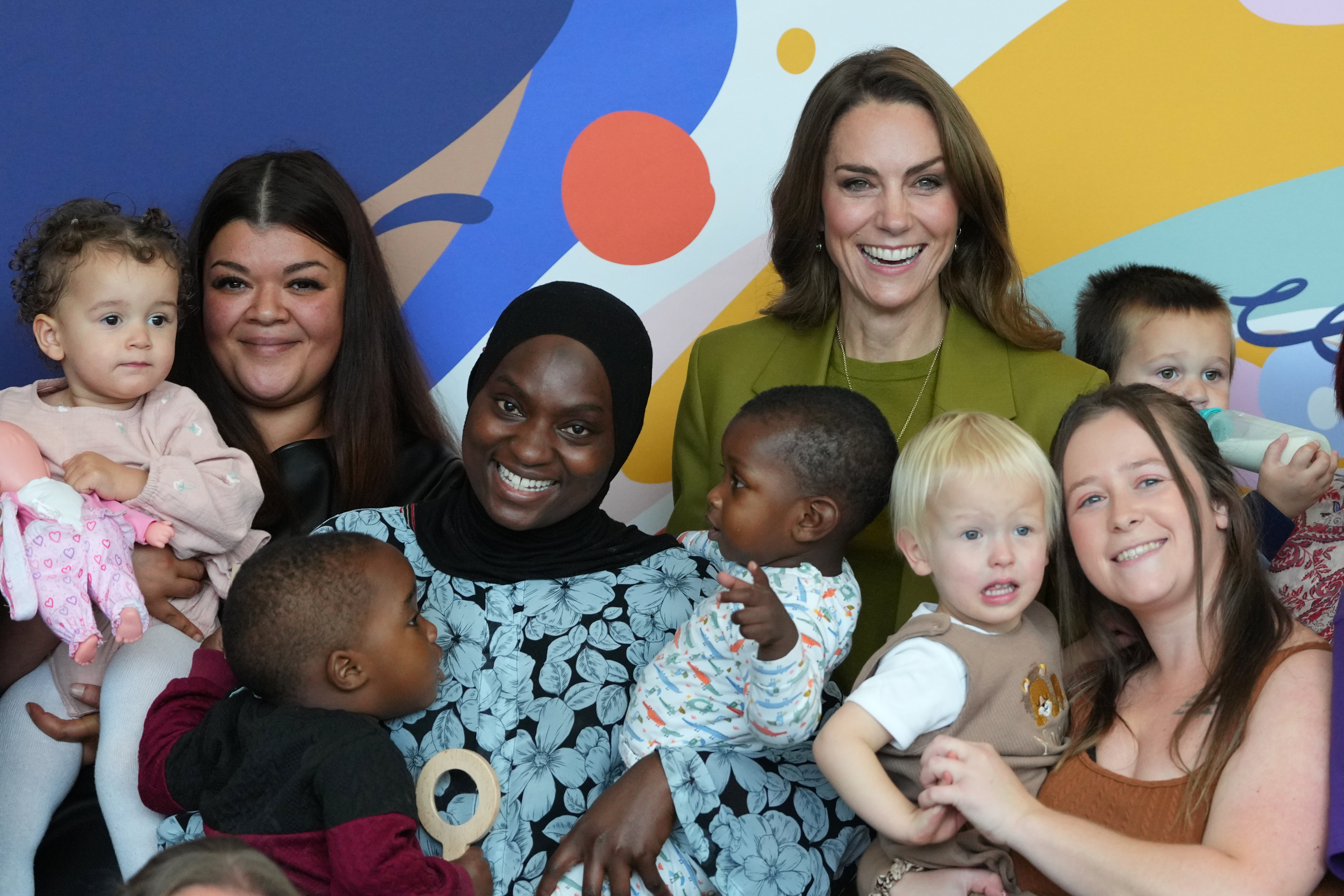 Kate Middleton posing with women and babies in a green suit
