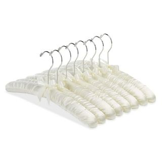 Eight cream satin padded clothes hangers stacked together. 