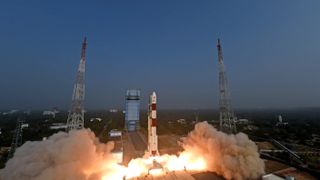 a red and white rocket launches into a dark-blue dusky sky.