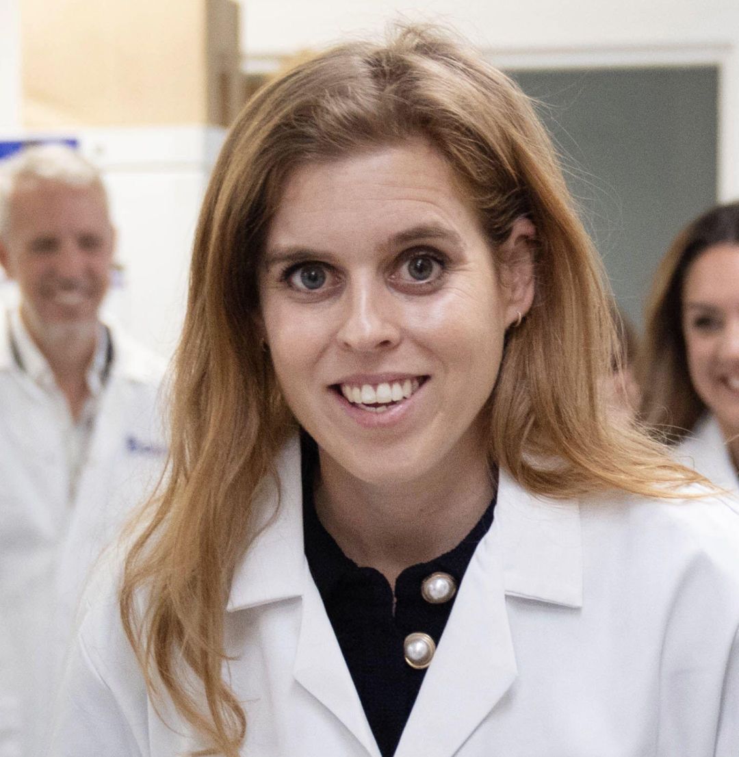 Princess Beatrice wearing a white lab coat and smiling