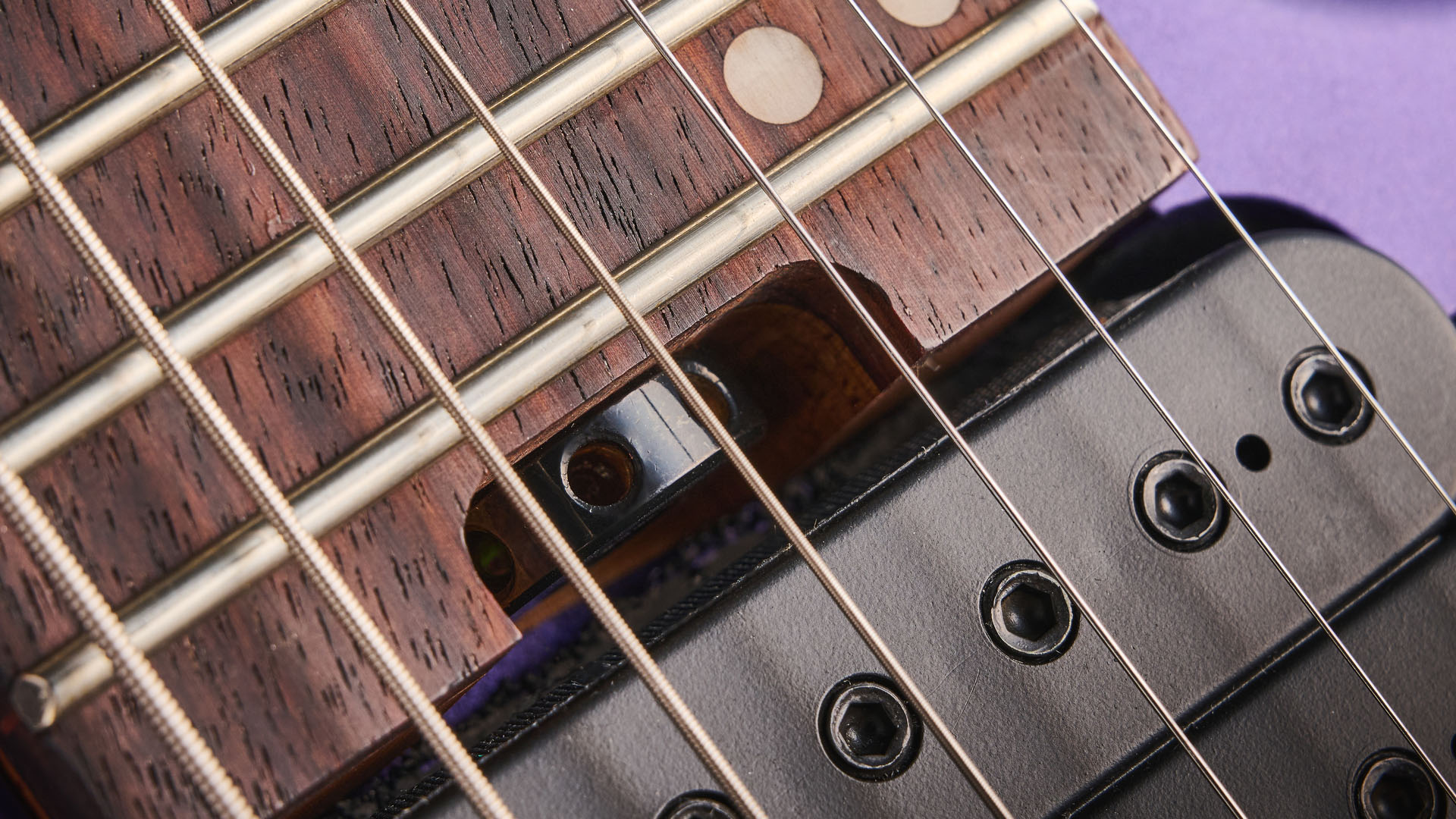 Sterling By Music Man Kaizen 7-string in Firemist Purple Satin, shot in close-up.