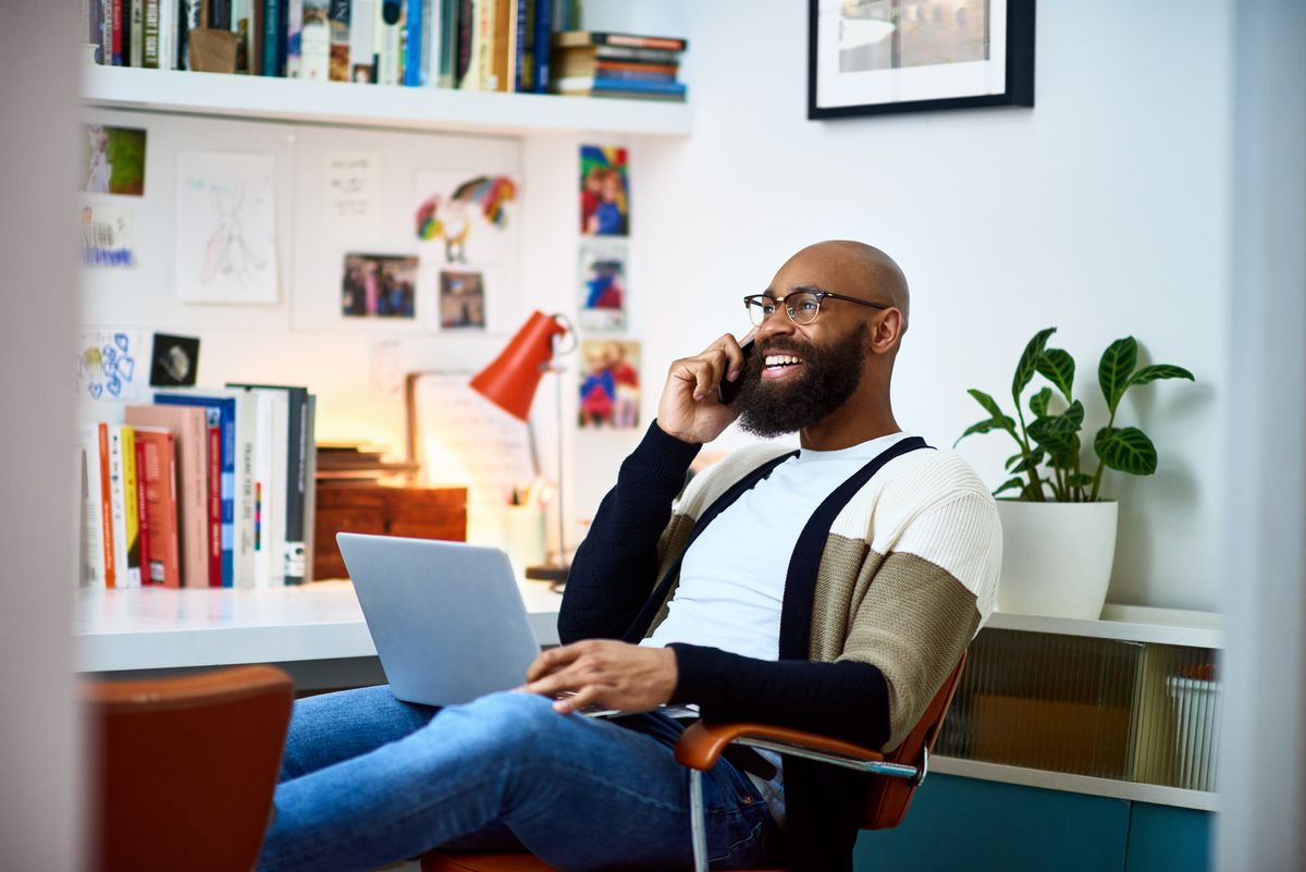 Cheerful businessman working from home on phone 