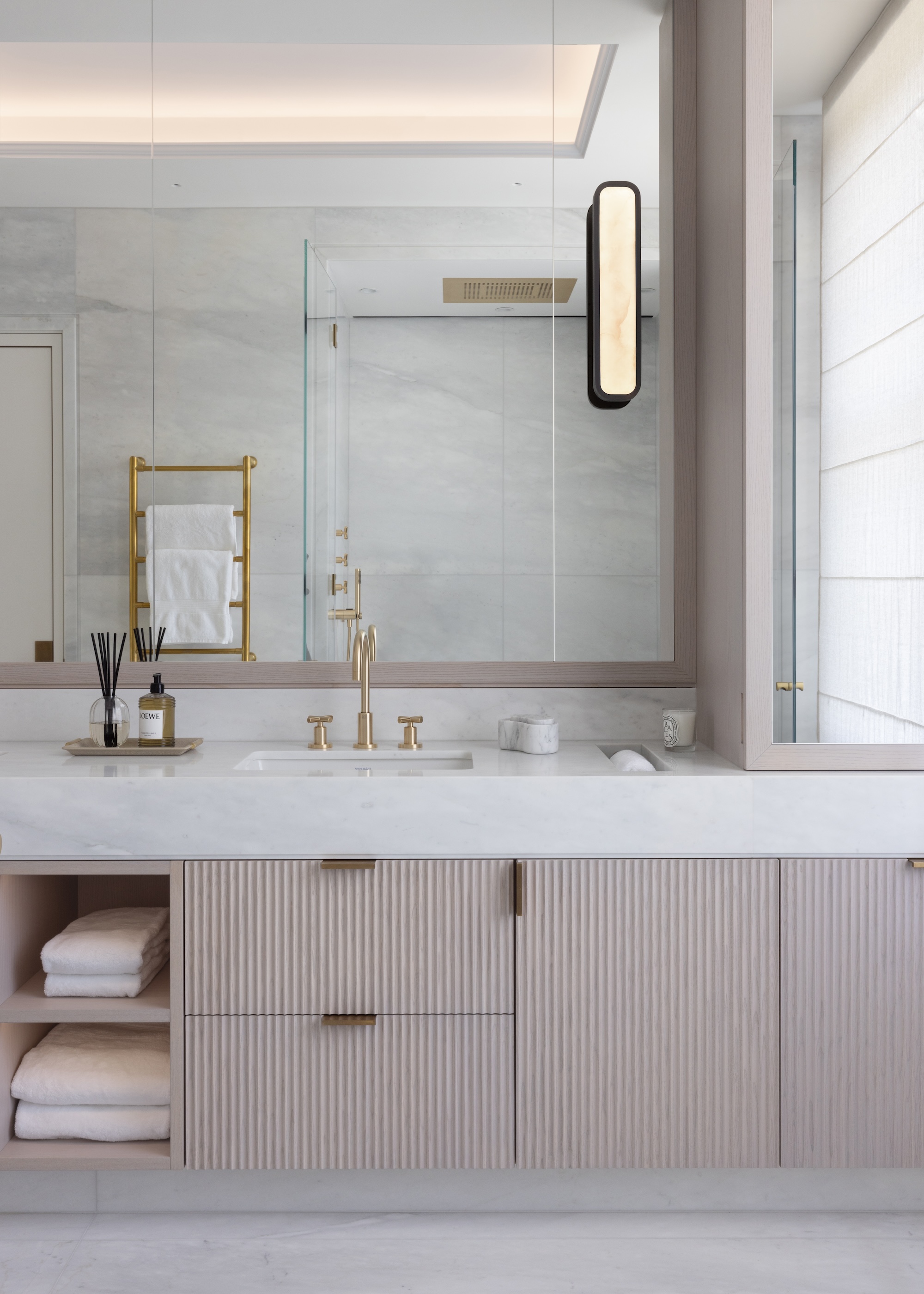 A calm and light-filled bathroom shown with a wall hung vanity basin, space for towels and a wall of mirrors