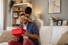 A happy father and son celebrating Father's Day with a cuddle and a gift.