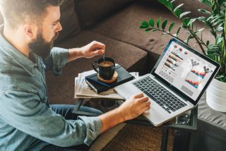 Bearded man working at laptop in coffee shop