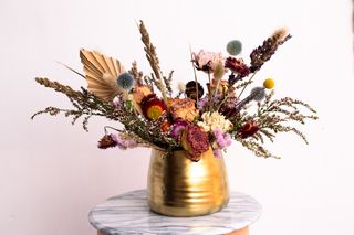 An assortment of dried flowers in a gold vase