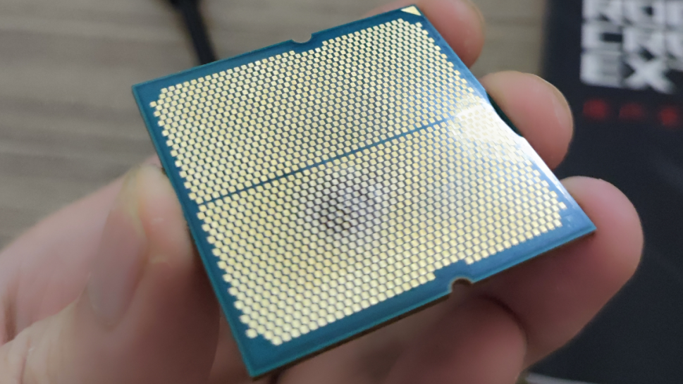 A close-up of a damaged Ryzen CPU showing a burned, distorted patch on the underside.