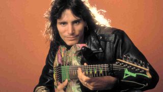 Steve Vai posing for a photograph while holding a guitar in 1990