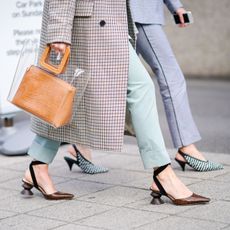 Two women walking down the street wearing heeled shoes.