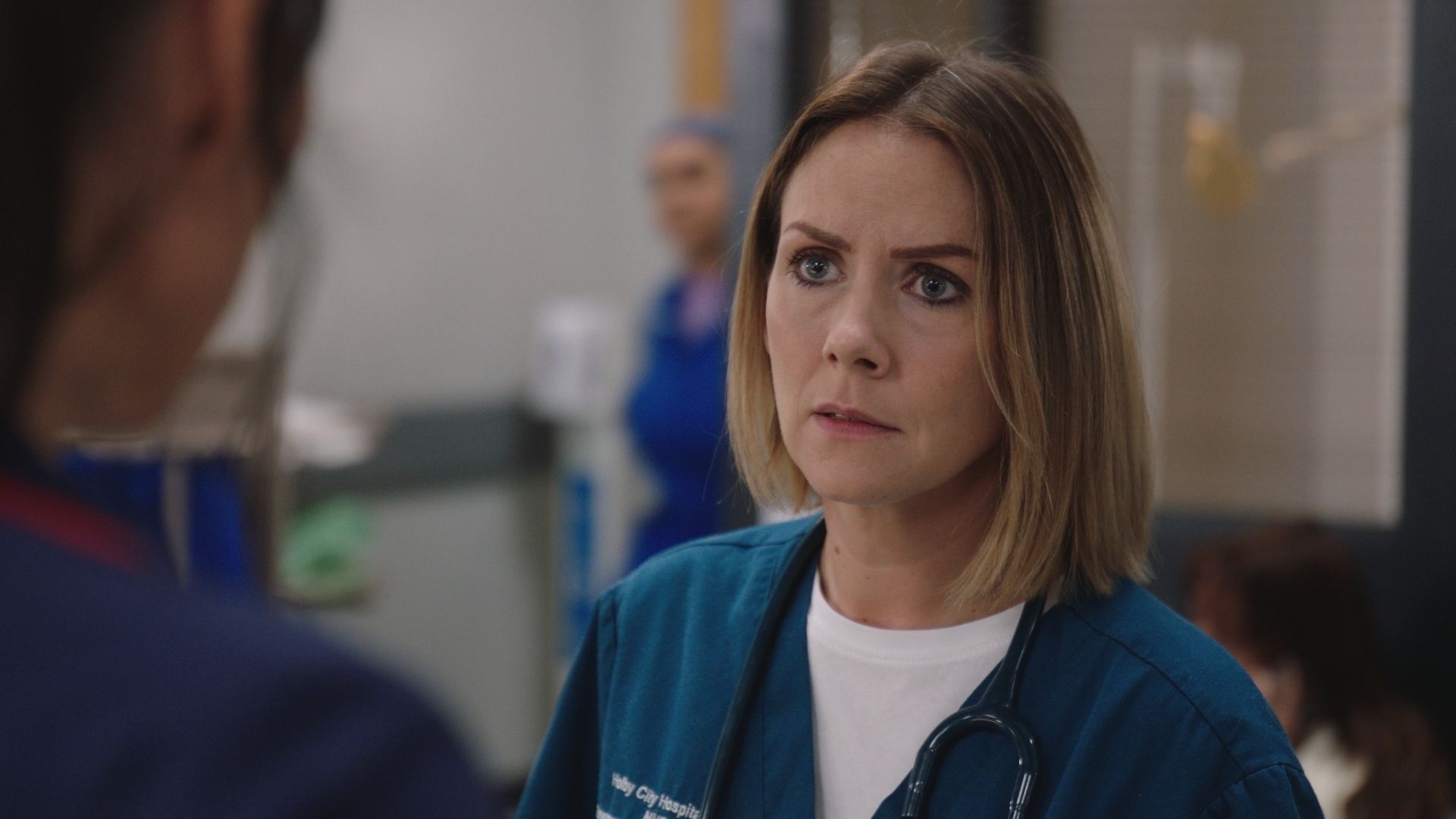 Stevie Nash at work, looking concerned while talking to Faith Dean.