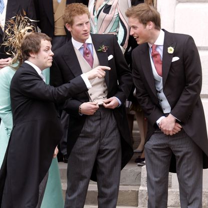 Tom Parker Bowles pointing while talking to Prince William and Harry, all of them wearing morning suits