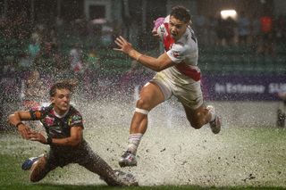 Rugby players spray mud up from the wet ground