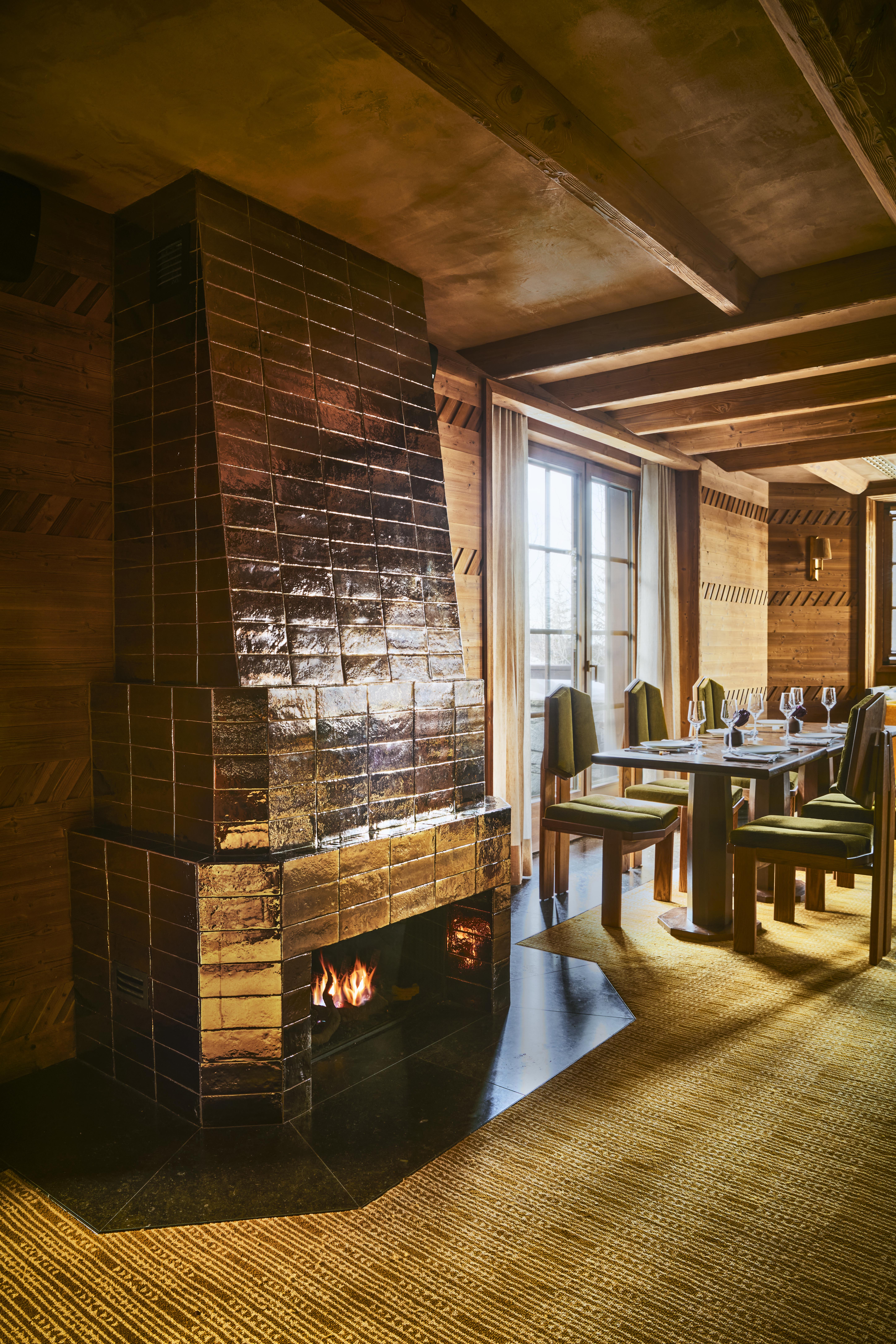 The elaborate, theatrical interiors of a ski chalet with wood wall paneling, plush textiles in different patternes, colors, and textures, plenty of paintings and sculptures adorning its halls, and a dimly lit atmosphere.
