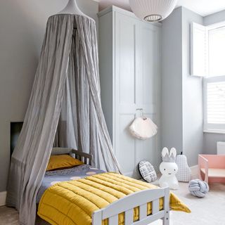 Grey nursery with fabric bed canopy and yellow comforter