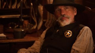 Billy Bob Thornton as Marshal Jim Courtright in 1883 sitting down and looking up over his hat.