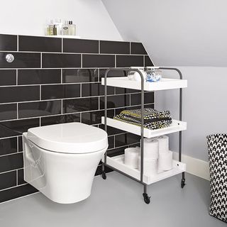 bathroom with grey tiled walls and wheeled troley