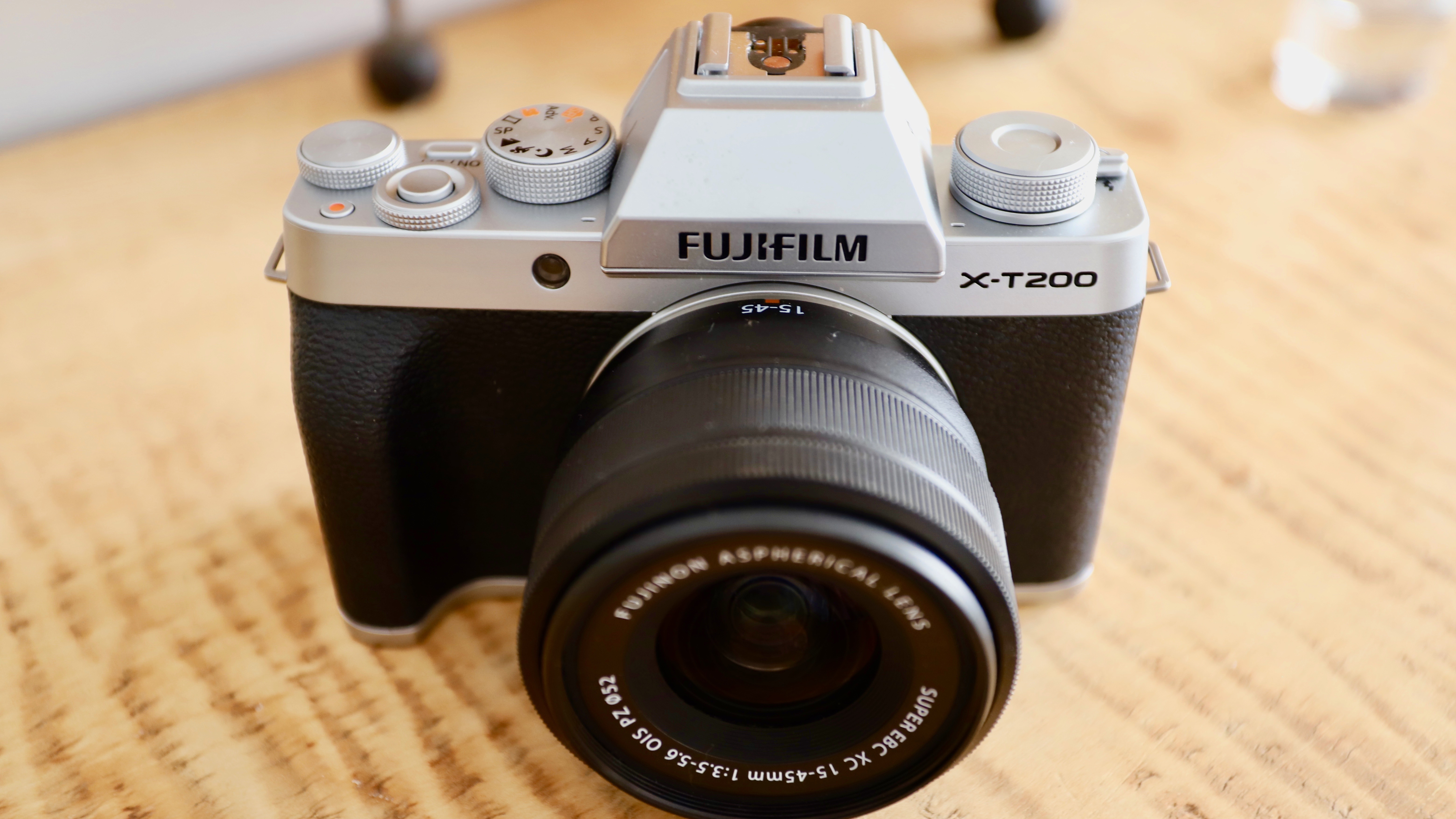 The Fujifilm X-T200 sitting on a wooden table with its 18-55mm kit lens