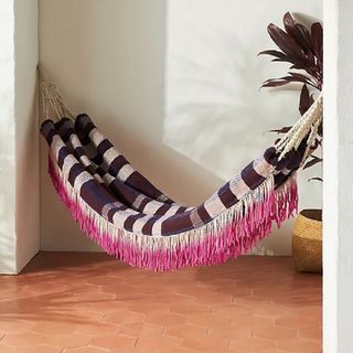 A hammock with pink fringing detail and stirpes