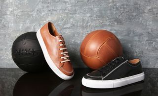 Two oversized woven loafers, one in tan one in black, Tan shoe resting on a black ball, black shoe next to a tan ball