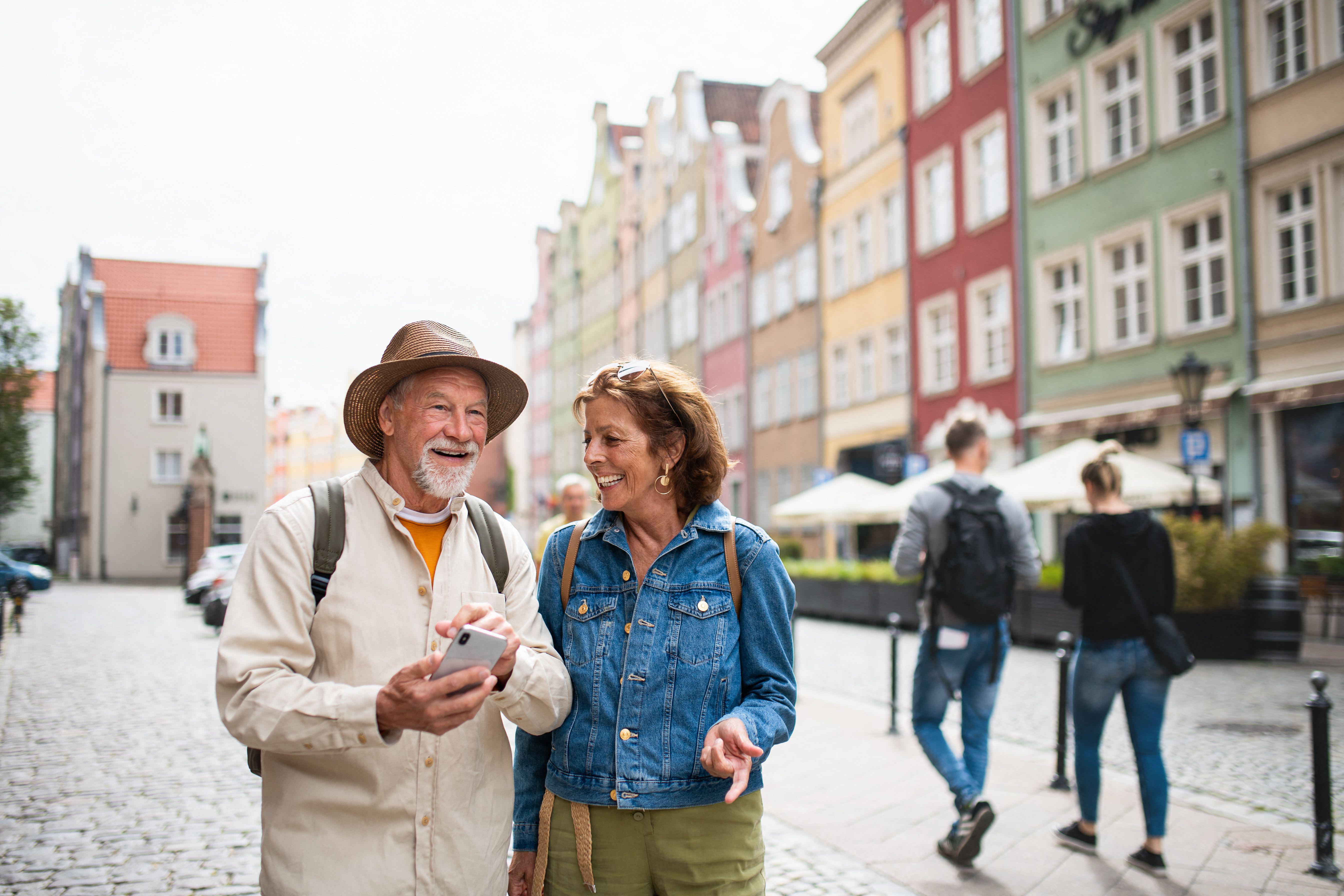 2J7XF16 Portrait of happy senior couple tourists using smartphone outdoors in historic town