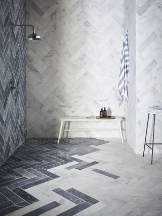 bathroom with marble floor and walls, chevron pattern, shower, shower bench