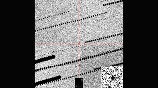 A gray grainy image with a red cross hair in the middle zooming in on a black dot against the grains