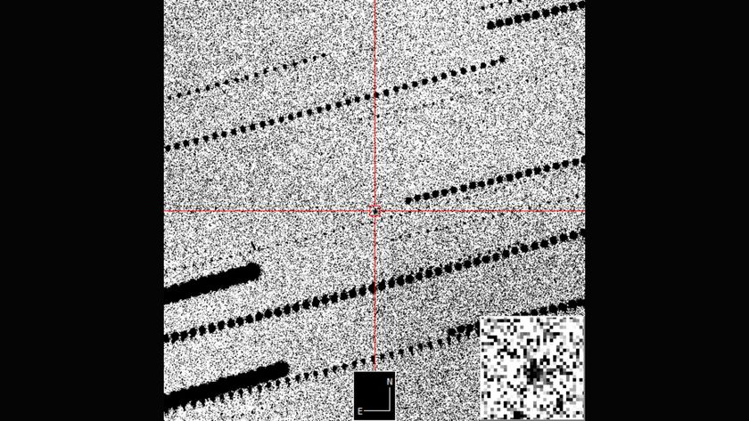 A gray grainy image with a red cross hair in the middle zooming in on a black dot against the grains