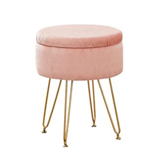 A small pink storage ottoman with gold legs