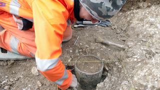 An archaeologist with Wessex Archaeology excavates a Bronze Age pot discovered during preliminary work on the site of the proposed tunnel near Stonehenge.