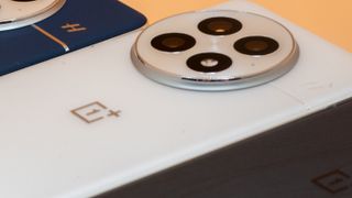 OnePlus 13 in white up close showing camera, next to blue and black models