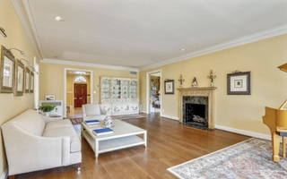 A living room with a white couch, yellow waslls and wooden flooring