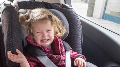 A toddler crying in her car seat 