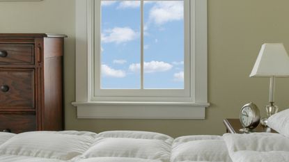best cooling mattress toppers: Cooling mattress topper on bed with window with blue sky outside 