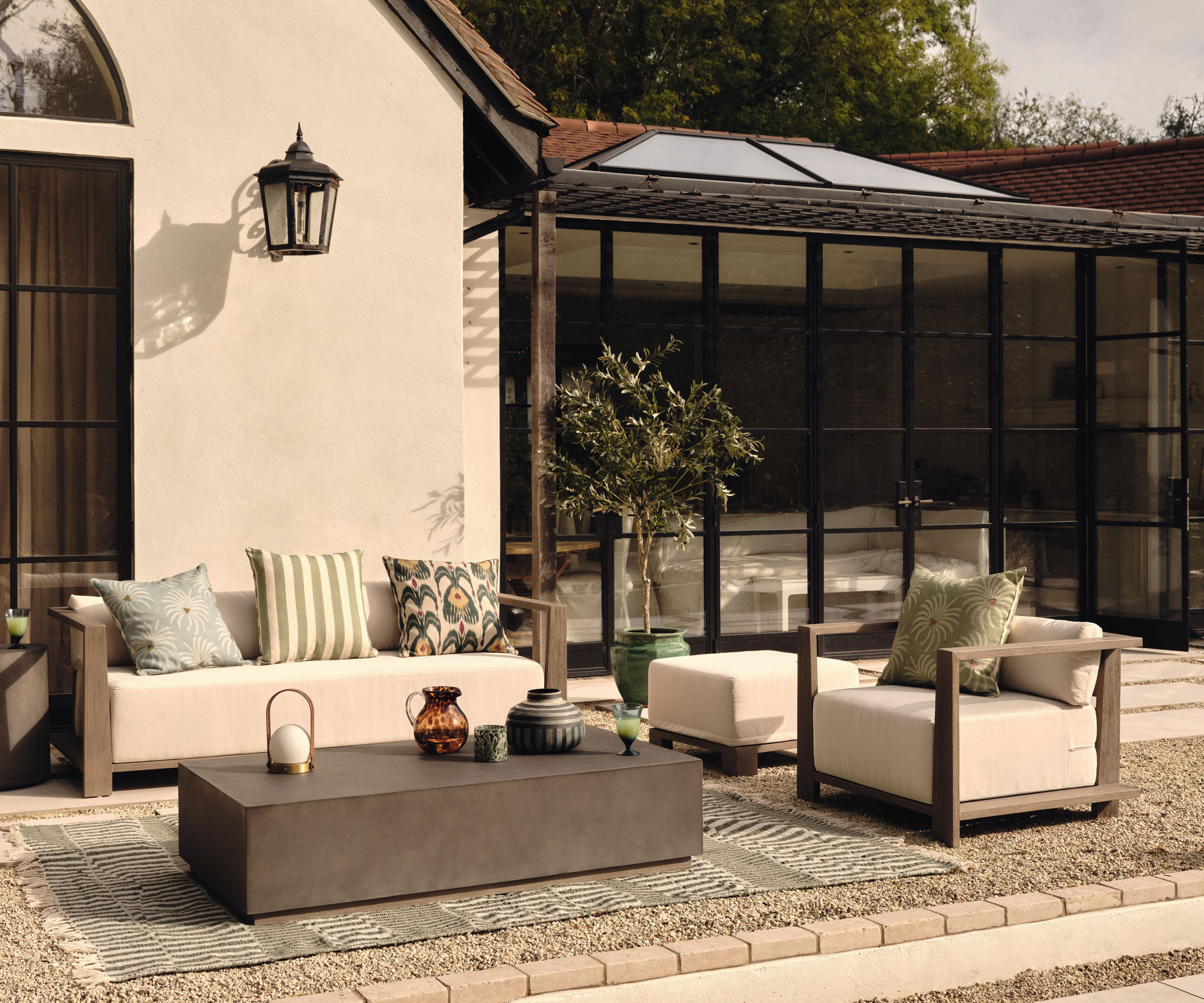 patio with garden furniture, outdoor rug and accessories, with house and patio doors, and a small ornamental tree in a pot